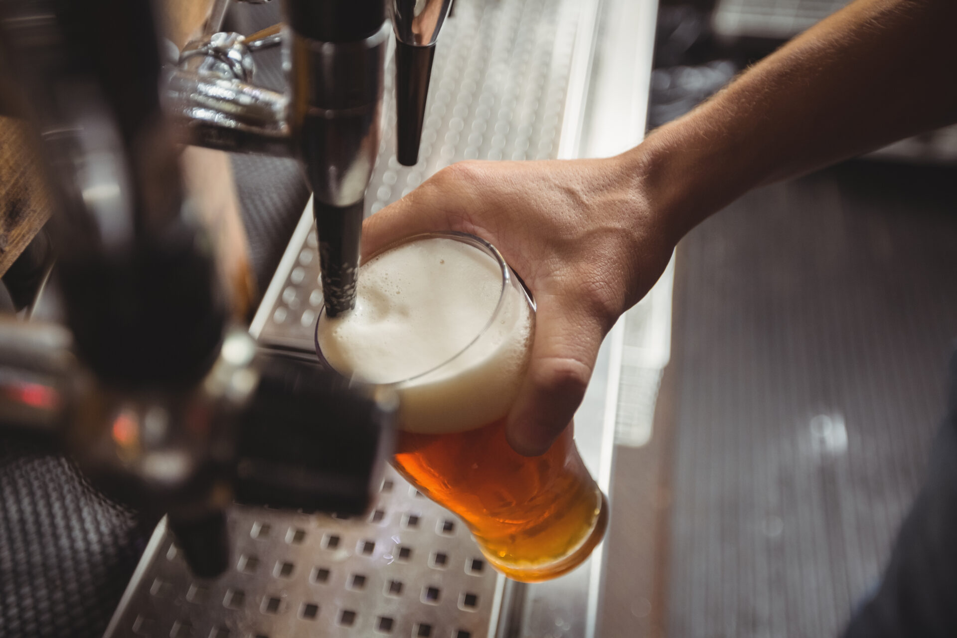 Close-up of bar tender filling beer from bar pump at bar counter